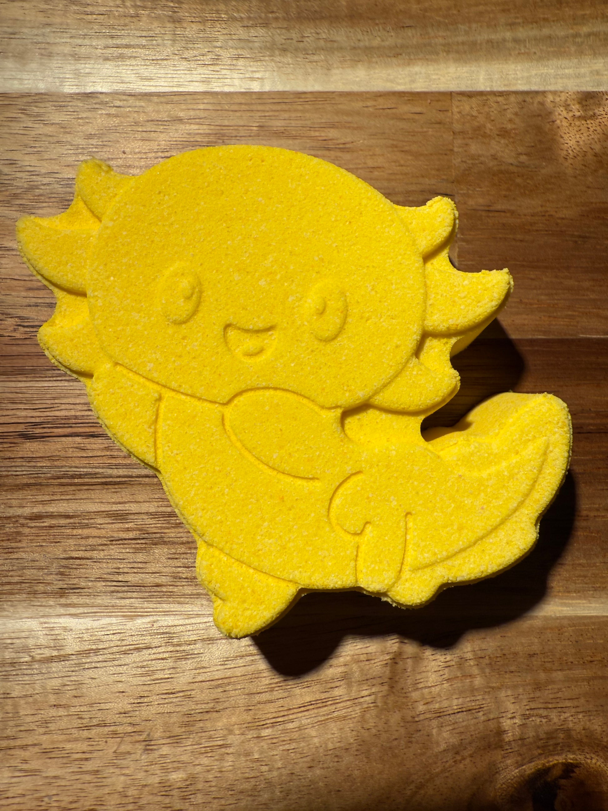 Yellow axolotl-shaped object on a wooden surface